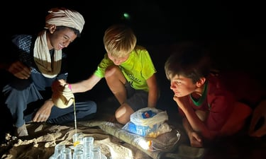 Two boys with a nomad guide pouring tea at a camp in the Moroccan Sahara