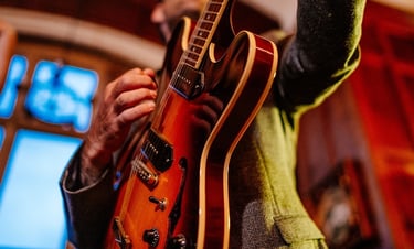 a man holding a guitar and playing a guitar