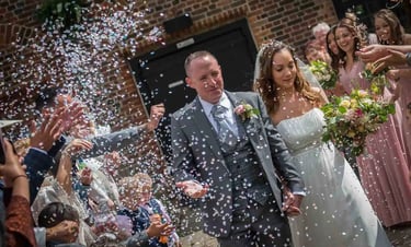 newly-wed running through confetti being thrown by guests