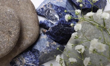 Piedras naturales de sodalita azul con rocas de río grises y flores de aliento de bebé blancas