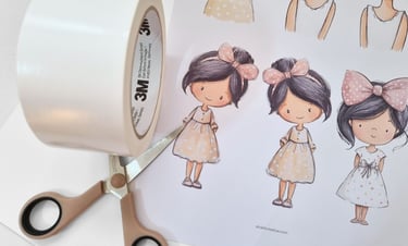 Printed sheet with cute girls on it. Double-sided tape and scissors next ot it.