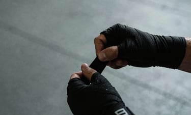 Close-up of athletic hands wrapping black handwraps in a raw concrete gym, dramatic side-lighting, cool desaturated tones, 35mm documentary style.