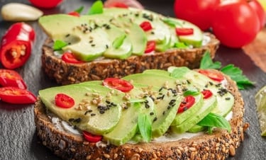 Avocado toast on multigrain seeded bread topped with chili peppers and sesame seeds.