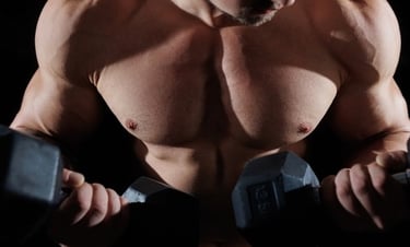 Close-up of a muscular man doing dumbbell curls to build biceps and chest muscles in a gym.