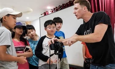 a man holding explaining a camera to kids