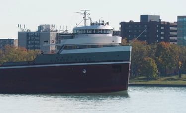 Close-up of the forward pilothouse of freighter Wilfred Sykes passing apartment buildings.