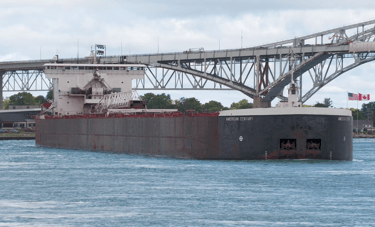 Huge black and white freighter American Century in front of the Blue Water Bridge.