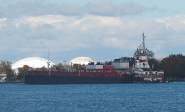 Tugboat Albert pushes barge Margaret past and industrial site.