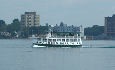 A green and white Soo Locks tour boat passing by on the St. Marys River.