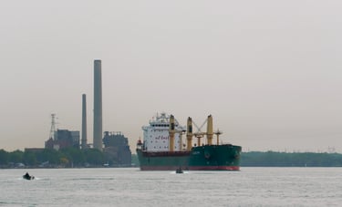 Green and white oceangoing ship with yellow deck cranes, passes 2 small boats.
