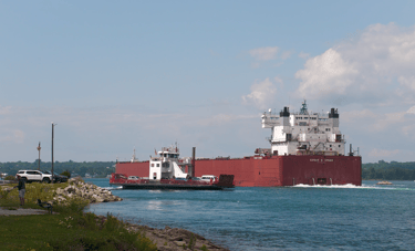 The Sugar Island ferry passing a giant red freighter at Mission Point.