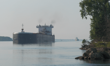 Huge black and white freighter approaches Mission Point, with a smaller freighter following behind.