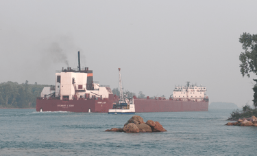 Soo Marine Supply boat Ojibway pulls along side huge freighter Stewart J. Cort.