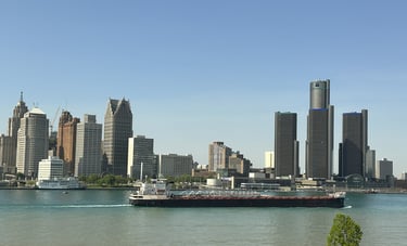 A black and white ship passing the downtown Detroit skyline.