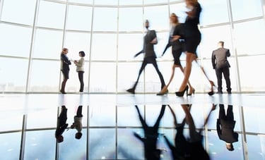 a group of business people walking through a large glass window