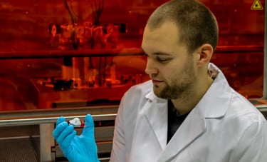 a man in a lab coat and gloves holding a 3D bioprinted nose model. Bioprinter in the background.