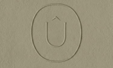 Logotipo minimalista en relieve que presenta una U con un circunflejo dentro de un óvalo.