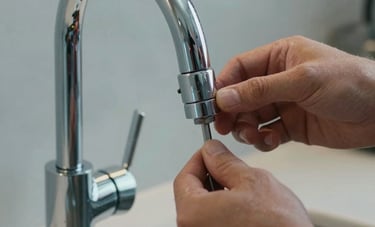 Close-up of a modern, high-end chrome faucet being installed by a professional in a clean North American kitchen. The shot is focused on the hands and professional tools, conveying knowledgeable service and attention to detail. Soft natural light, steel blue and light grey tones.