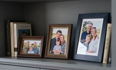 A tranquil, high-end residential interior in the British countryside, representing a secure home environment. The focus is on a shelf with family photos and books, symbolizing the protection of family assets and wealth preservation. Photography style is sharp and modern, with a sophisticated color palette of slate gray and navy.