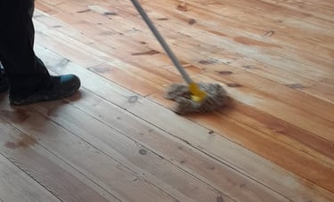 a person cleaning a hardwood floor with a broom