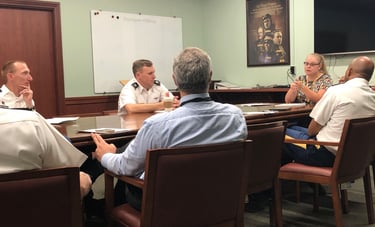 Dr. Hooton sitting at a table leading a discussion with instructors about presentation strategies