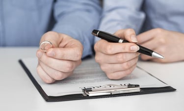 a man and woman holding a pen and writing on a piece of paper