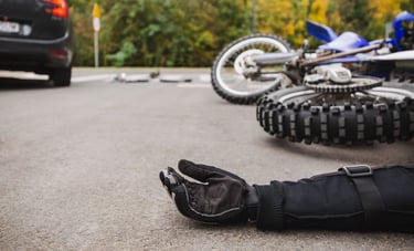 Motorcycle Accidents scene showing a rider’s gloved hand on the road and a fallen motorcycle after a collision, illustrating
