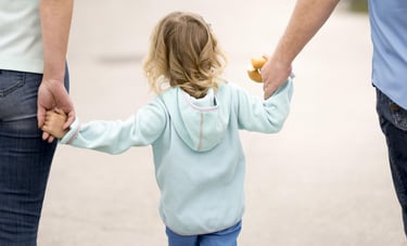 Adoption and guardianship concept, young child holding hands with two adults, representing family ca