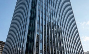 The exterior architectural detail of a modern steel and glass skyscraper in a major US financial center, reflecting the clear blue sky, emphasizing stability, height, and forward-thinking engineering in a professional atmosphere.