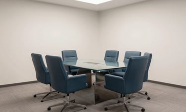 An interior shot of a sophisticated, modern North American conference room. A minimalist glass table and comfortable blue-grey designer chairs. The composition is clean and centered, emphasizing clarity and professionalism. Soft overhead lighting. Colors include dark teal and off-white.
