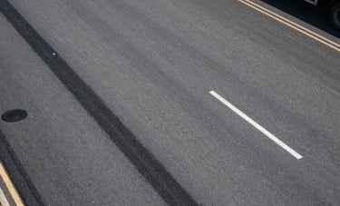 An aerial-angle shot of a logistics yard in the UK, showing clean asphalt and a recently completed, professional pothole repair that blends perfectly into the surface.