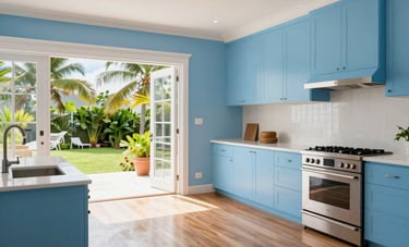 A wide-angle shot of a luxurious interior renovation in a Jamaican villa. The space features fresh light blue and white paint, polished wood floors, and modern fixtures. Large windows overlook a tropical garden, emphasizing a clean and sophisticated finished look.