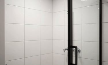 Professional photography of a bathroom shower stall with pristine, reglazed white wall tiles and black grout lines. A sleek, modern aesthetic in a Manhattan apartment. Clean, airy composition with high contrast between the white tiles and dark hardware.