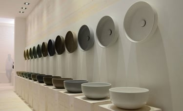 Exposição de cubas minimalistas alinhadas em diferentes cores e formatos em showroom de design conte