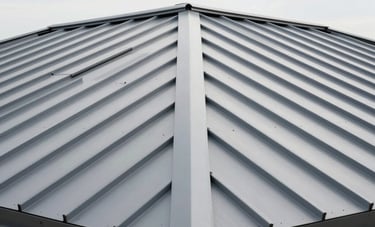 A clean, modern perspective of a newly installed steel gray metal roof on a high-end property. The composition emphasizes strength, durability, and precise craftsmanship. North American / NYC architecture under a bright white sky.