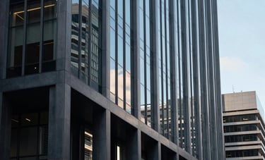 An architectural shot of a contemporary corporate building in Melbourne, Oceania / Australian region. Glass facade reflecting a clear sky. Sophisticated, established feel with strong leading lines. Palette features steel blue and muted slate blue tones.