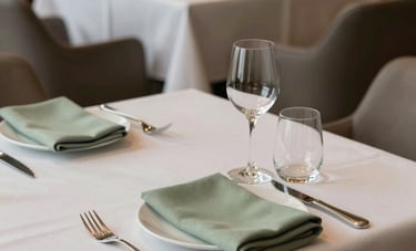 A tranquil fine dining restaurant scene in a Turkish boutique hotel. Minimalist table setting with off-white linens, delicate sage green napkins, and natural light. Sophisticated atmosphere.
