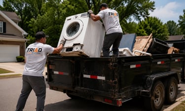 Professional junk removal team loading a washing machine into a disposal truck.