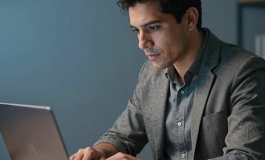 A focused Latinoamericano / Hispano male expert analyzing social media engagement metrics on a laptop in a minimalist workspace, steel blue accents in the background, professional and efficient mood.
