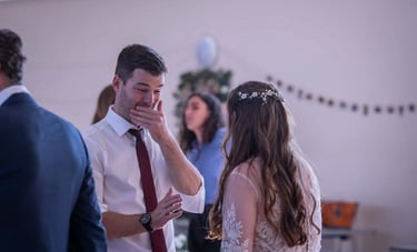 An emotional wedding guest crying while talking to a bride in a white lace dress.