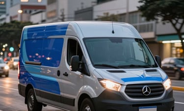 A modern silver delivery van with royal blue and light blue detailing driving through an avenue in a Brazilian metropolis at dusk. The city lights are blurred in the background, conveying speed.