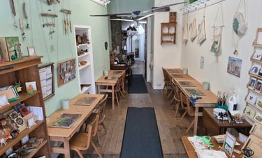 Dalbeattie Wood workshop with wooden work tables and chairs against opposite walls and various items on the walls.