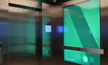 A sophisticated modern lift lobby in an upscale Indian corporate office building, featuring high-definition digital advertising screens embedded in the walls displaying dynamic content in Charcoal Blue and Emerald Green tones.