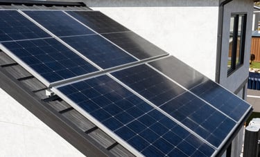 A technical architectural photograph showing modern solar panel arrays and battery storage systems integrated into a clean, modern home exterior, crisp lighting, North American / US setting.