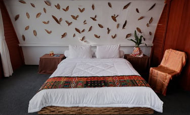 Cozy rustic bedroom with a white duvet, traditional patterned runner, and autumn leaf wall decor.