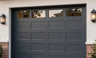 A beautiful modern dark gray steel garage door with horizontal glass windows, installed on a contemporary US-style luxury home with brick accents and clean landscaping.