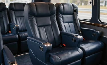 A photograph of the interior of a luxury corporate coach with plush deep navy leather seating, integrated power outlets, and warm ambient lighting, North American business context.