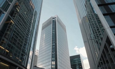 A wide-angle, low-perspective shot of the sleek glass facades of skyscrapers in the City of London, United Kingdom. The reflection of a clear blue sky and the surrounding modern architecture creates a forward-thinking and sophisticated mood. Professional lighting emphasizing cool light grey and muted blue tones.