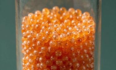 Close-up of orange indicating silica gel beads in a sophisticated glass vessel. The beads show a vibrant orange hue against a dark Matte Forest Green backdrop. Sharp focus on the texture of the desiccant, clean and technical look, with professional studio lighting.