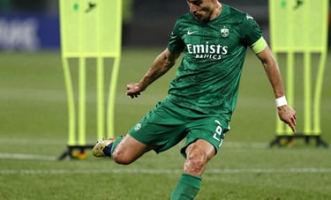 Dynamic action shot of a professional soccer player executing a powerful strike on a lush grass pitch. High-contrast lighting highlights Performance Green and Energetic Lime training markers in the background. Global / Spanish-speaking environment.